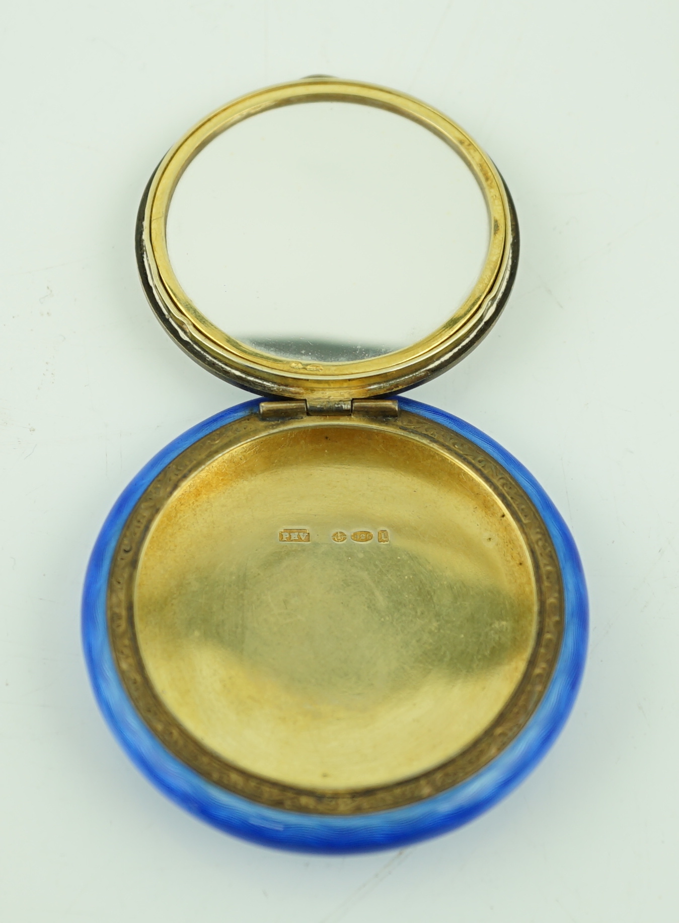 A George V silver gilt and enamel circular compact, decorated with a seated dog, import marks for P.H. Vogel